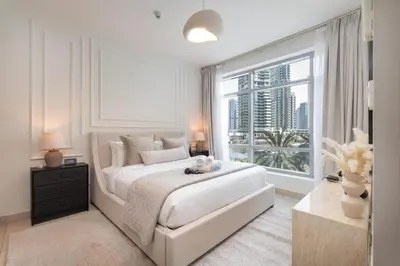 a bedroom with a large white bed and a large window at Bright, modern flat on the Marina Promenade in Dubai