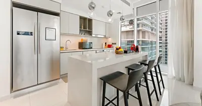 a kitchen with a bar with stools and a refrigerator at Luxury 3BHK & Maid Sea View & Private Beach in Sabkhah