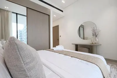 a white bedroom with a bed and a mirror at Serene 1BR Retreat W Private Pool Binghatti Royale in Dubai