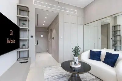 a living room with a white couch and a table at Elegant Designer Studio with Balcony & Rooftop Pool in JVC in Dubai