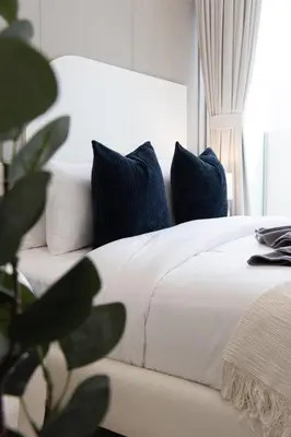a bedroom with a white bed with blue pillows at Elegant Designer Studio with Balcony & Rooftop Pool in JVC in Dubai