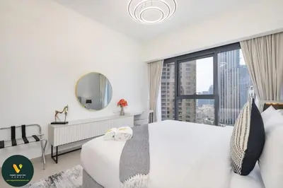 a bedroom with a large white bed and a large window at Vogue Downtown Act One near Burj Khalifa and Dubai Mall, Two Bedroom Apartment with Balcony and City Skyline View, Access to all Amenities in Dubai