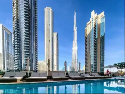 a pool with chairs and buildings in a city at Vogue Downtown Act One near Burj Khalifa and Dubai Mall, Two Bedroom Apartment with Balcony and City Skyline View, Access to all Amenities in Dubai
