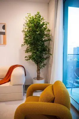 a living room with a yellow chair and a plant at Luxury 1 Bedroom - Burj Khalifa & sea view - Sauna & Pool - High Floor in Dubai
