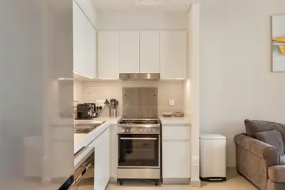 a kitchen with white cabinets and a stove top oven at Premium 2BR with Park View in Dubai Creek Harbour in Dubai