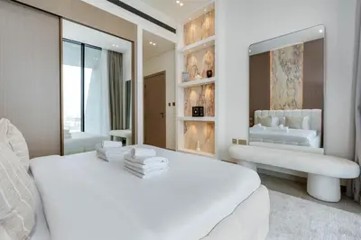 a white bedroom with a large white bed and a mirror at Private pool, Paddle court, Sauna and Hammam - Binghatti Royal in Dubai