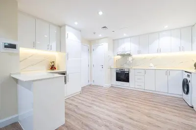 a white kitchen with white cabinets and a wooden floor at Stunning 2BR with Sea View Murjan 1 Near Beach in Dubai