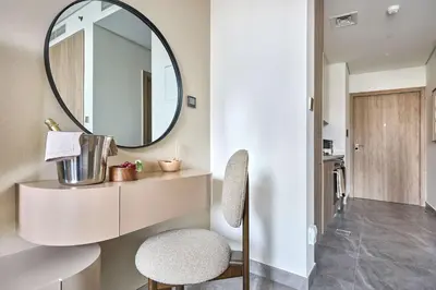 a bathroom with a round mirror and a stool at Frank Porter - Peninsula One in Dubai