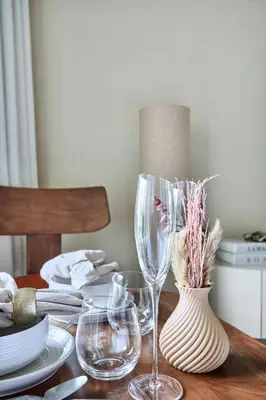 a wooden table with wine glasses and a vase with flowers at Frank Porter - Peninsula One in Dubai
