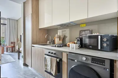 a kitchen with a washing machine and a microwave at Frank Porter - Peninsula One in Dubai