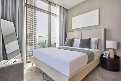 a bedroom with a large bed and a large window at Frank Porter - Peninsula One in Dubai