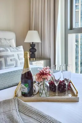 a tray with a bottle of wine and glasses on a bed at Frank Porter - Downtown Views II in Dubai