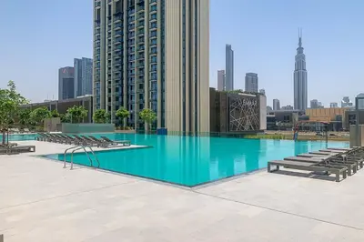 a large swimming pool with chairs and a city skyline at Frank Porter - Downtown Views II in Dubai