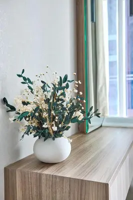 a white vase with flowers on a wooden table at Frank Porter - J One Tower, Business Bay in Dubai
