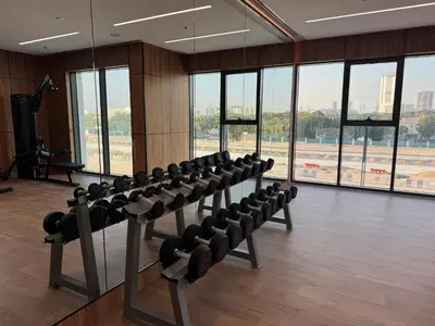 a gym with a row of exercise equipment in a room with windows at Elegant Retreat Studio in Azizi Mirage in Dubai