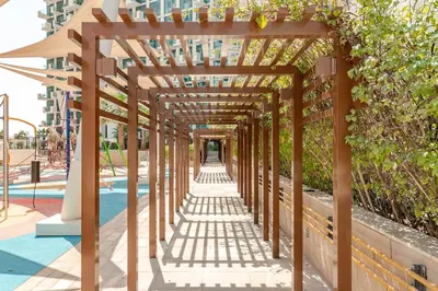 a wooden pergola over a walkway at a playground at Stylish Studio near Downtown with pool in Dubai