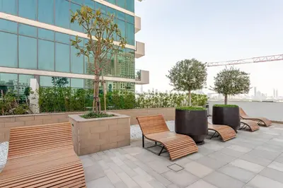 a row of chairs and trees in front of a building at Stylish Studio near Downtown with pool in Dubai