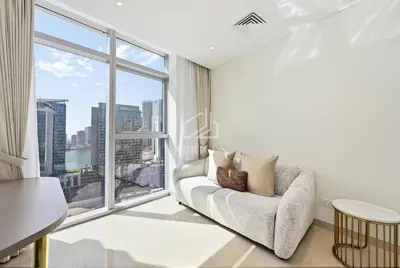 a living room with a couch and a large window at Luxury Urban Living at Imperial Avenue, Downtown in Dubai