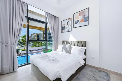 a white bedroom with a large bed and a pool at Bloomfields Cozy 1BR Azizi Riveria 47 in Dubai