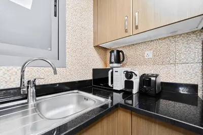 a kitchen with a sink and a coffee maker on a counter at Elegant 1BR Apartment in Ikarus, Dubai Production City in Dubai