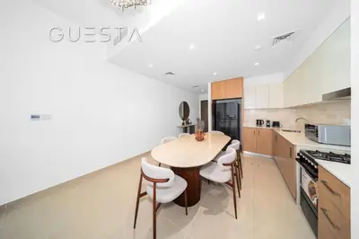 a kitchen with a wooden table and stools at Seagate by Emaar, Mina Rashed Marina, Dubai in Dubai