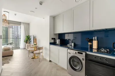 a kitchen with white cabinets and a washing machine at Chic Studio in Peninsula Three, Business Bay in Dubai