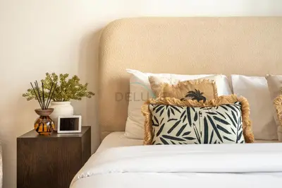 a bed with a pillow and a night stand next to it at Open layout Studio with Balcony - Azizi Riviera 67, Al Merkadh by Deluxe Holiday Homes in Dubai