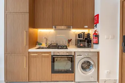 a kitchen with a washing machine and a stove at Open layout Studio with Balcony - Azizi Riviera 67, Al Merkadh by Deluxe Holiday Homes in Dubai