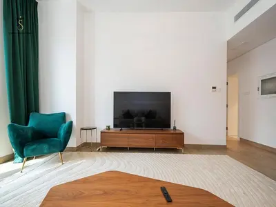 a living room with a television and a green chair at Luxury Loft 1 Bedroom La Voile - Building 1 Jumeirah 1 in Dubai