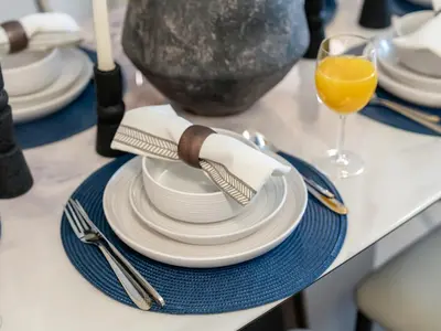 a table with white plates and a glass of orange juice at Royal Vista25 - 4BR with Billiard Table at Forte Tower Downtown Dubai in Dubai