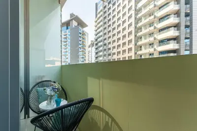 a balcony with two chairs and a table with a vase of flowers at PVH - Seven Palm - Modern Studio with Beach Access near Palm Jumeirah Mall in Dubai