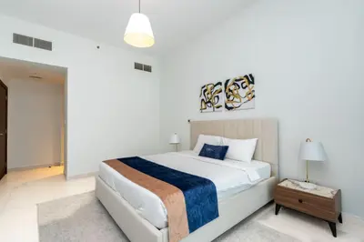 a white bedroom with a large bed and a table at CitiHome - Spacious 2BR - Park Gate Residences in Dubai