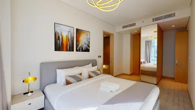 a bedroom with a large white bed and a room with a bed sqor at Vacationer l Vida T2 1 Bedroom l Direct Access to Dubai Mall in Dubai