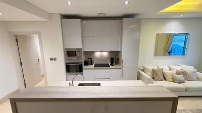 a living room with a white couch and a kitchen at Beachfront comfort your private escape at Palm jumeriah th8 residences in Dubai