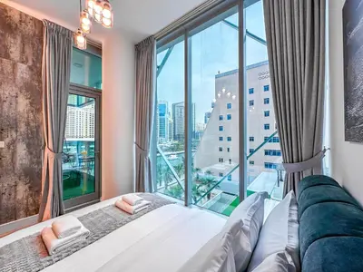 a bed in a room with a large window at Marina Elegance, Walk to JBR Beach and Ain Dubai w Stunning Canal View in Dubai