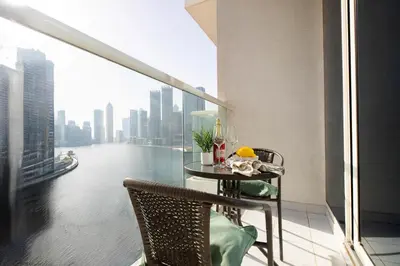 a table and chairs on a balcony with a view of a river at Frank Porter - Damac Maison Prive in Dubai