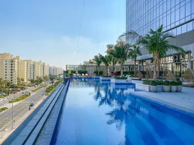a large swimming pool with palm trees and buildings at Sunset Bliss Elegant Palm Island Studio in Dubai