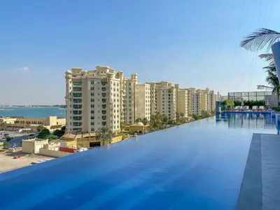a large swimming pool with a view of a city at Sunset Bliss Elegant Palm Island Studio in Dubai