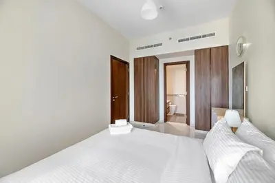 a bedroom with a white bed and a bathroom at Modern 2BR I DAMAC Reva Residences I Canal Views in Dubai