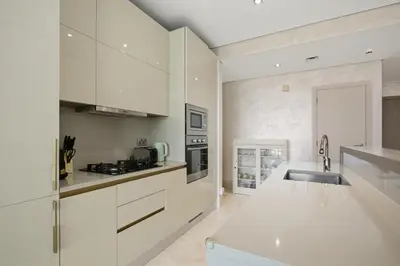 a white kitchen with white cabinets and a sink at Stunning 2 Bedroom in Palm with private beach in Dubai