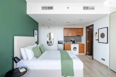 a bedroom with a large white bed and a kitchen at Silkhaus Studio Burj Daman with Burj Khalifa View in Dubai