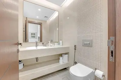 a bathroom with a toilet and a sink and a mirror at Nobles Tower- Luxe with Skies-High 1BR Lifestyle in Dubai
