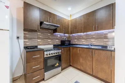 a kitchen with wooden cabinets and a stove at HAVN - Studio in Botanica, JVC in Dubai