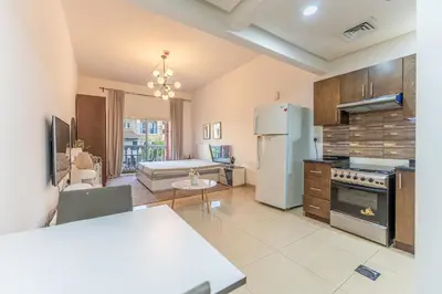 a large kitchen with a refrigerator and a table at HAVN - Studio in Botanica, JVC in Dubai