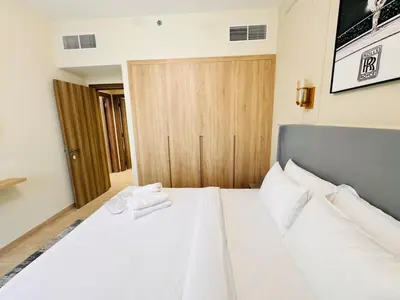 a bedroom with a white bed with a wooden door at Celestial 2BR with Burj Khalifa View in Dubai