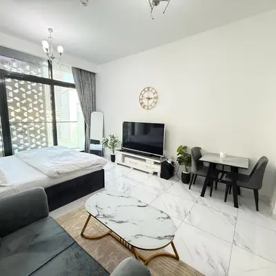 a white living room with a television and a table at An elegant sanctuary in Dubai