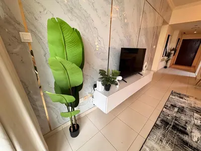 a living room with a green plant and a tv at Skylux Bright 1BR with Canal Views & Extra Bed in Dubai