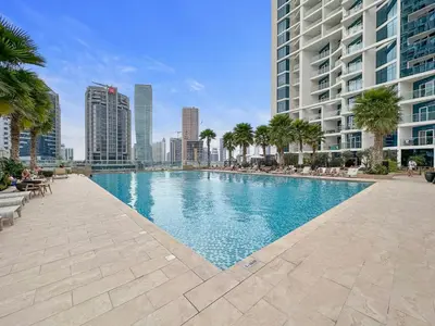 a swimming pool in a city with tall buildings at Luxe 1BR with Balcony & Canal View in Dubai