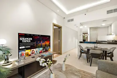 a living room with a tv and a dining room at Luxe 1BR with Balcony & Canal View in Dubai
