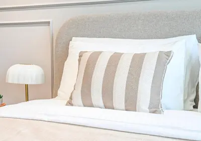 a bed with a striped pillow and a lamp at Stylish JVC Studio Hotel-Style Comfort in Dubai